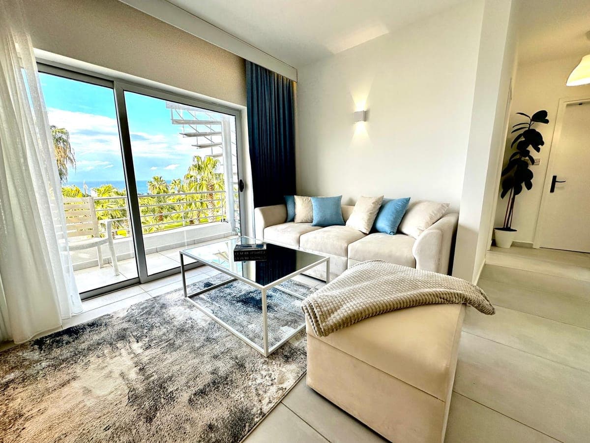 Living room with wide glass door, balcony and sea view.