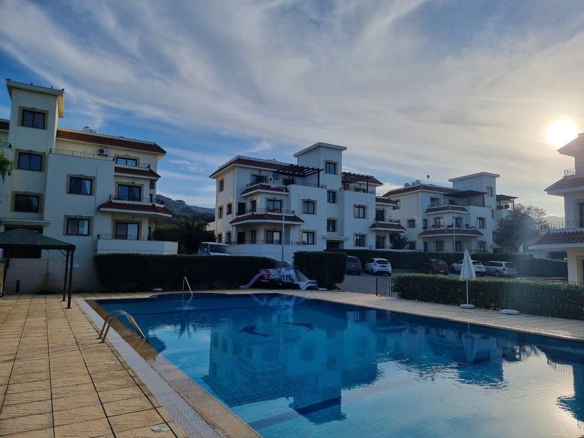 Exterior view of apartment buildings with shared pool and parking.