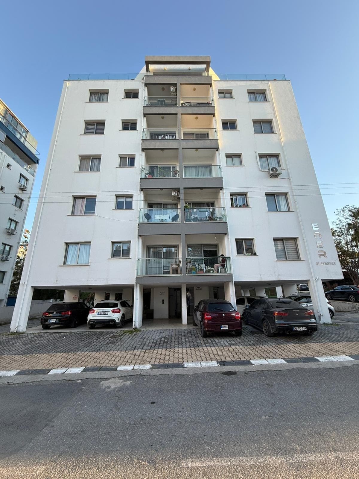 Exterior of a multi-story apartment building with ground floor parking.
