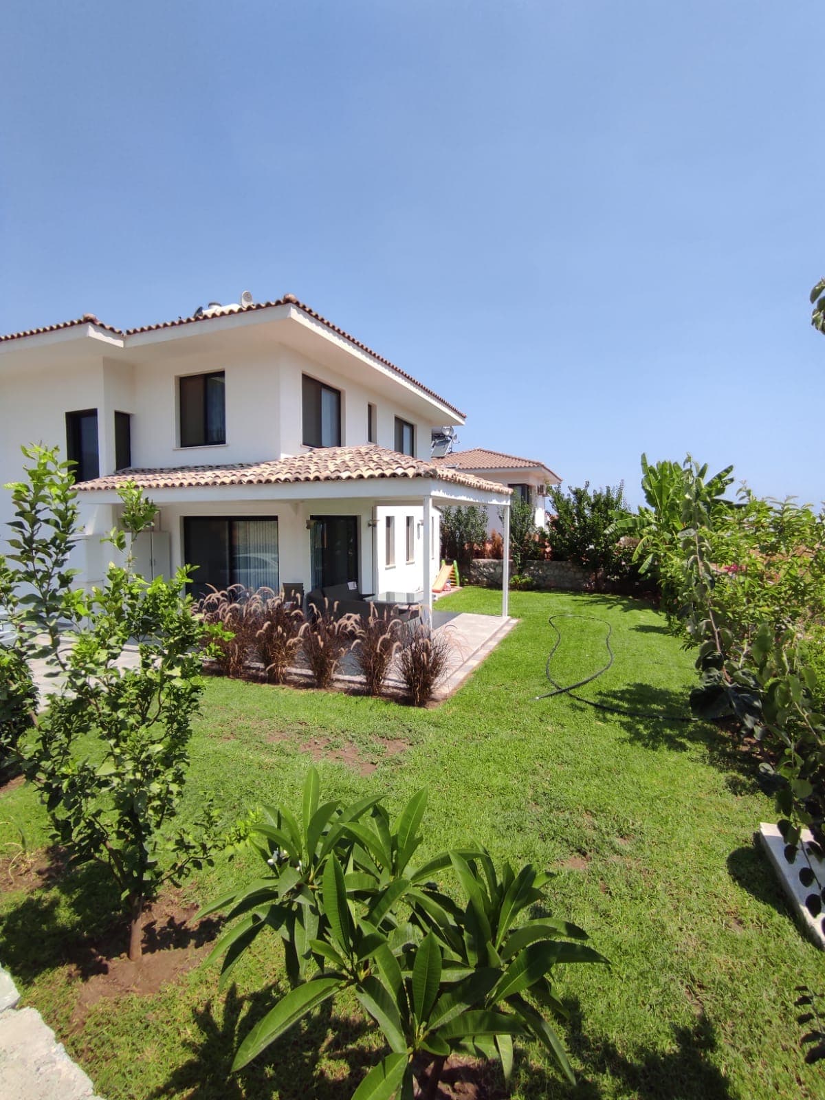 Exterior of a detached house with a large garden and veranda.